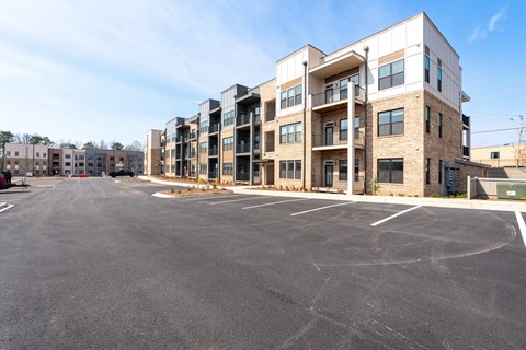 A large parking lot in front of a multi-story apartment building.
